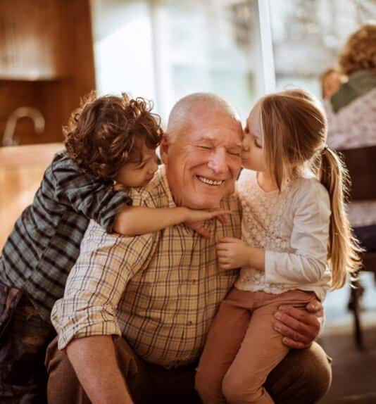 image of a grandfather getting hugged by his grandchildren