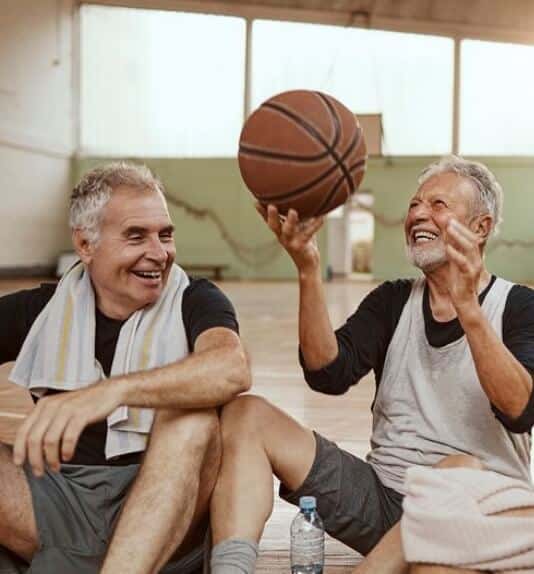 image of two older men sitting in a gym after playing basketball